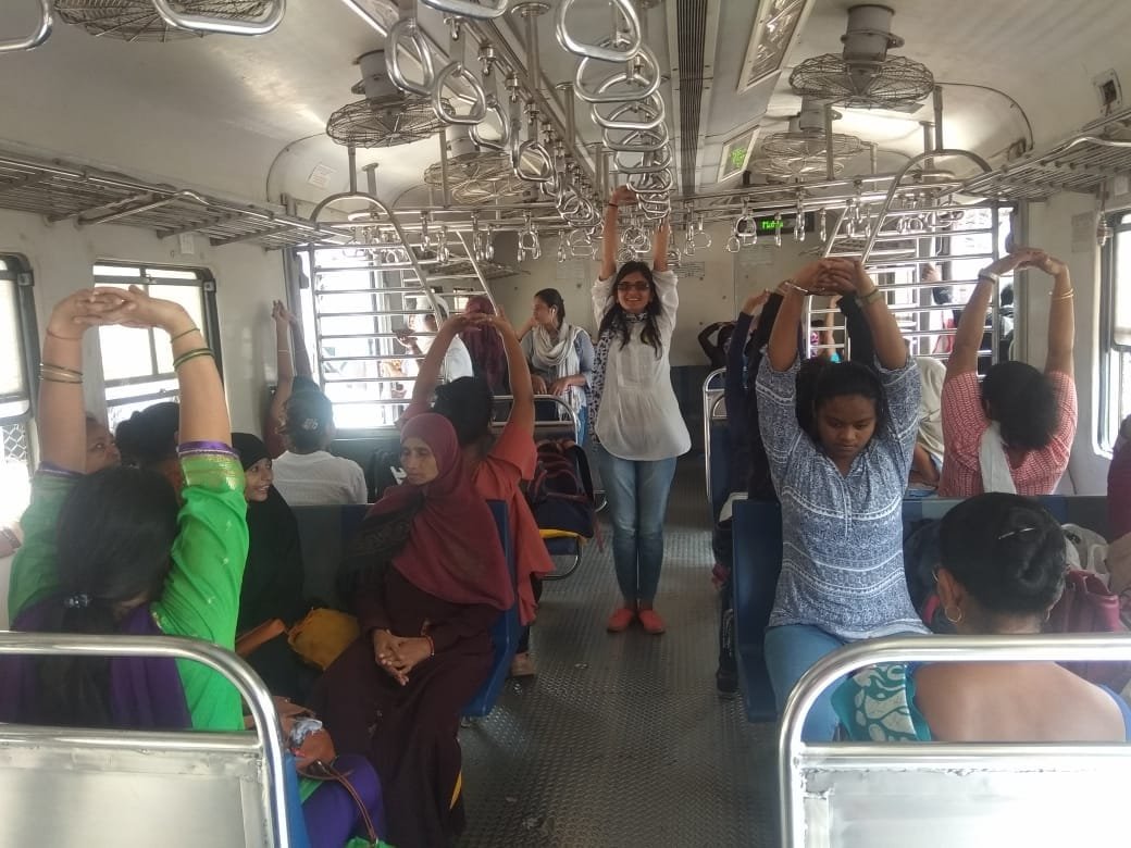Women on board a local train perform yoga during their commute